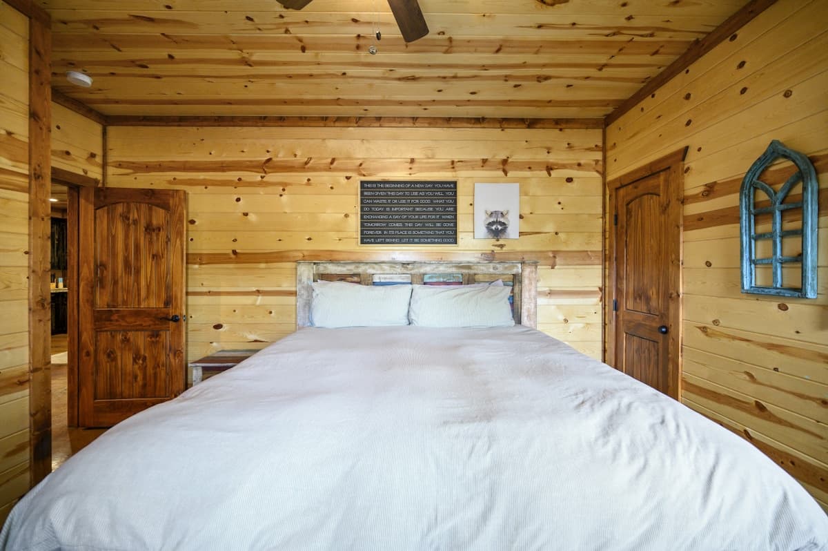 Main-floor bedroom at Livin' the Dream with a king bed, a rustic plank headboard and a ceiling fan