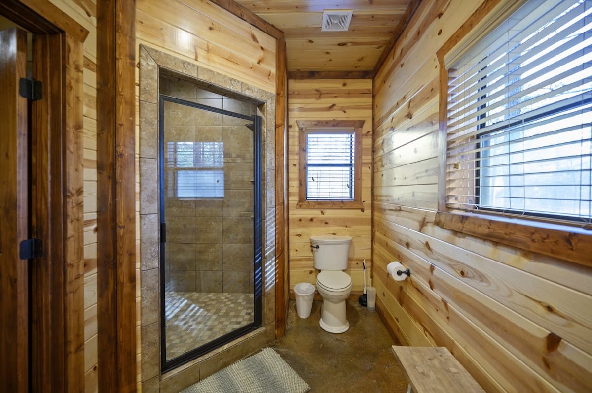 Bathroom at Livin' the Dream with a glass-door tile shower and pine plank walls