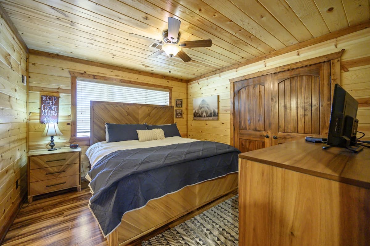 Upstairs bedroom at Livin' the Dream with a chevron wood headboard, navy bedding and a TV on a dresser
