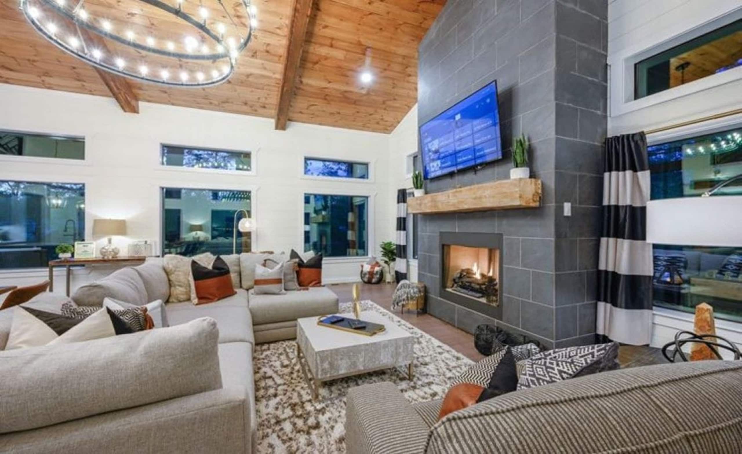 Great room at Sublime Retreat with a sectional sofa, a fireplace wall with a TV and a wood-plank vaulted ceiling