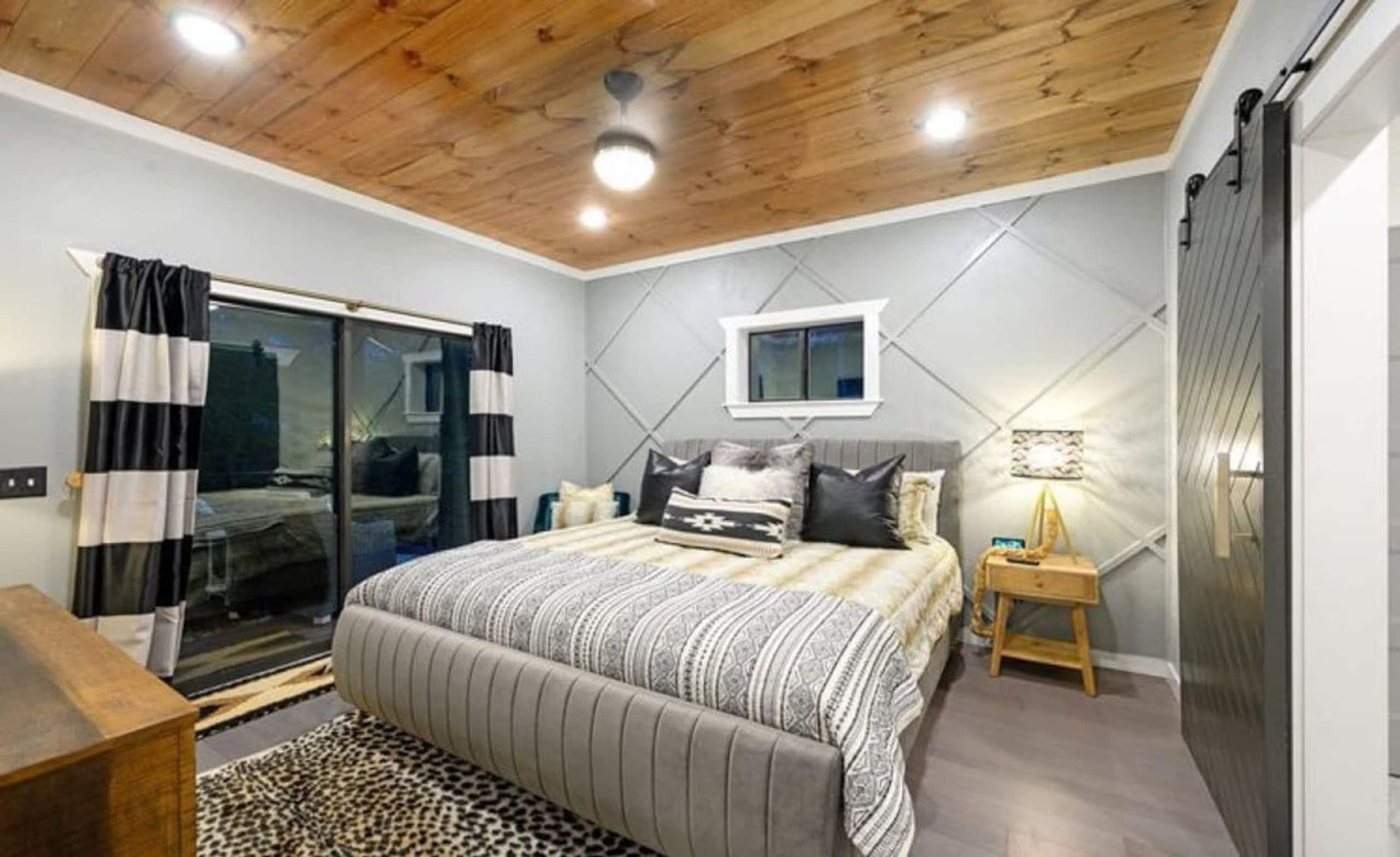 King suite at Sublime Retreat with an upholstered king bed, a diamond-molding accent wall and a sliding door to the patio