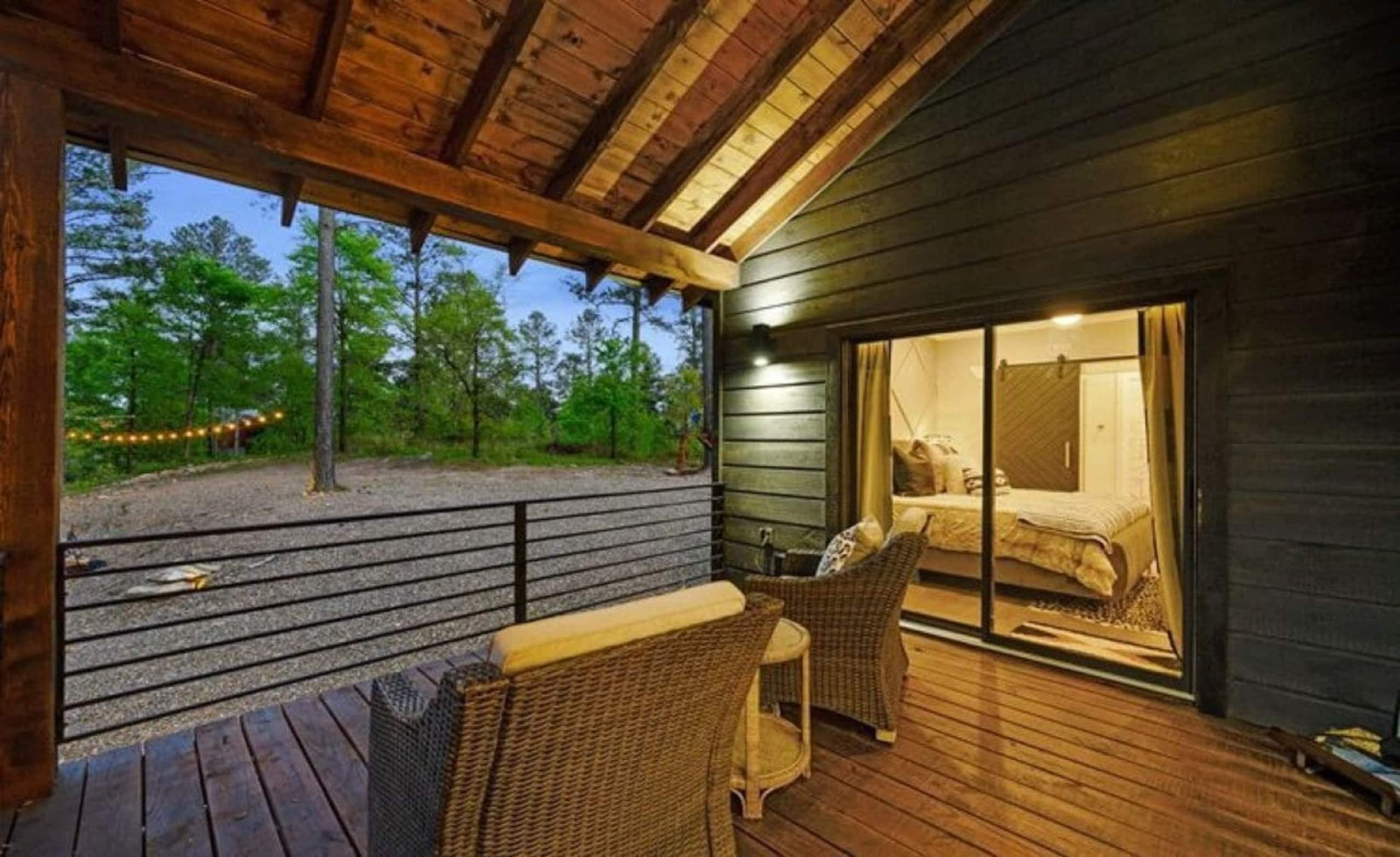 Private covered patio outside a king suite at Sublime Retreat, with wicker chairs and forest views